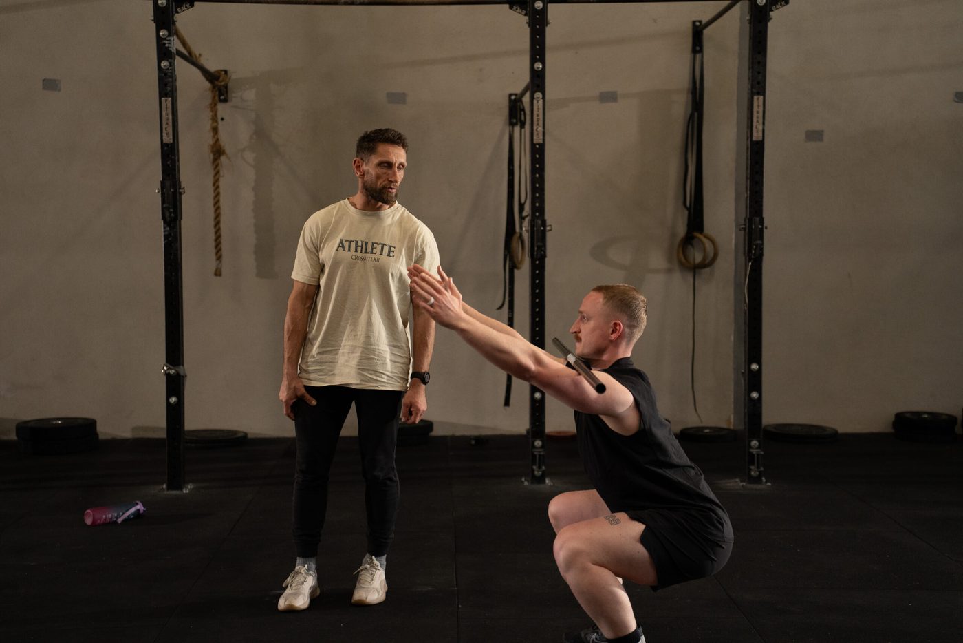 Un coach de CrossFit LXII observe le squat d'un membre
